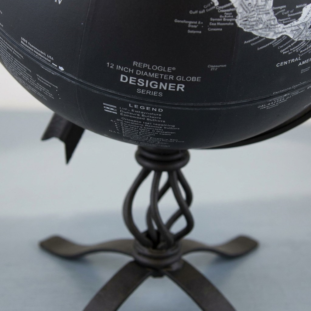 Extreme close-up of a dark globe showing highly detailed text and a spiral stand.