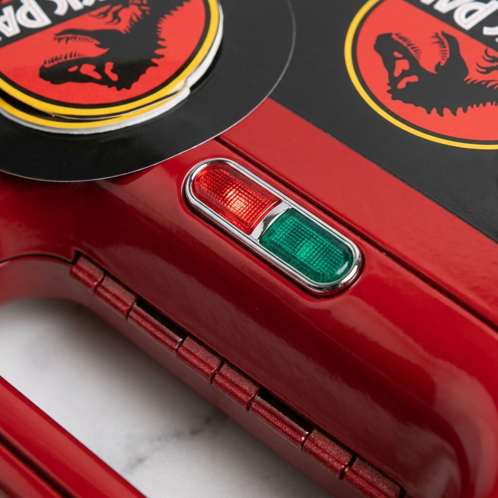 Close-up of red and green power indicator lights on the Uncanny Brands Jurassic Park sandwich maker.