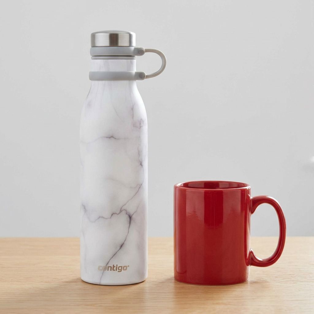 White marble Contigo Couture water bottle beside a red coffee mug on a wooden desk for size scale.